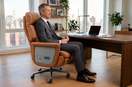 Tall executive seated comfortably in a leather office chair with full thigh support, feet flat on the floor, and proper backrest alignment.