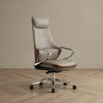 A modern high-back office chair upholstered in light taupe leather with dark brown leather trim, featuring chrome armrests and a five-star metal base with black casters, set against a minimalist beige wall and light wood herringbone floor.