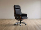 Black leather office chair on a wooden floor with a plain wall background