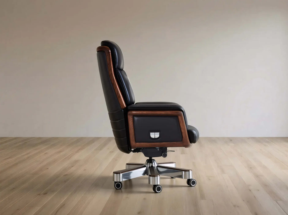 A high-back executive office chair with black leather upholstery and brown wood trim, mounted on a chrome five-star wheeled base, shown in profile against a neutral beige wall and light wood floor.