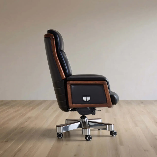 A high-back executive office chair with black leather upholstery and brown wood trim, mounted on a chrome five-star wheeled base, shown in profile against a neutral beige wall and light wood floor.