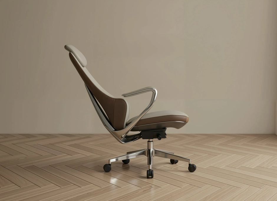 A modern office chair with a brown and beige upholstered seat and back, supported by a chrome metal frame and five-star base, set against a minimalist beige wall and light wood herringbone floor.