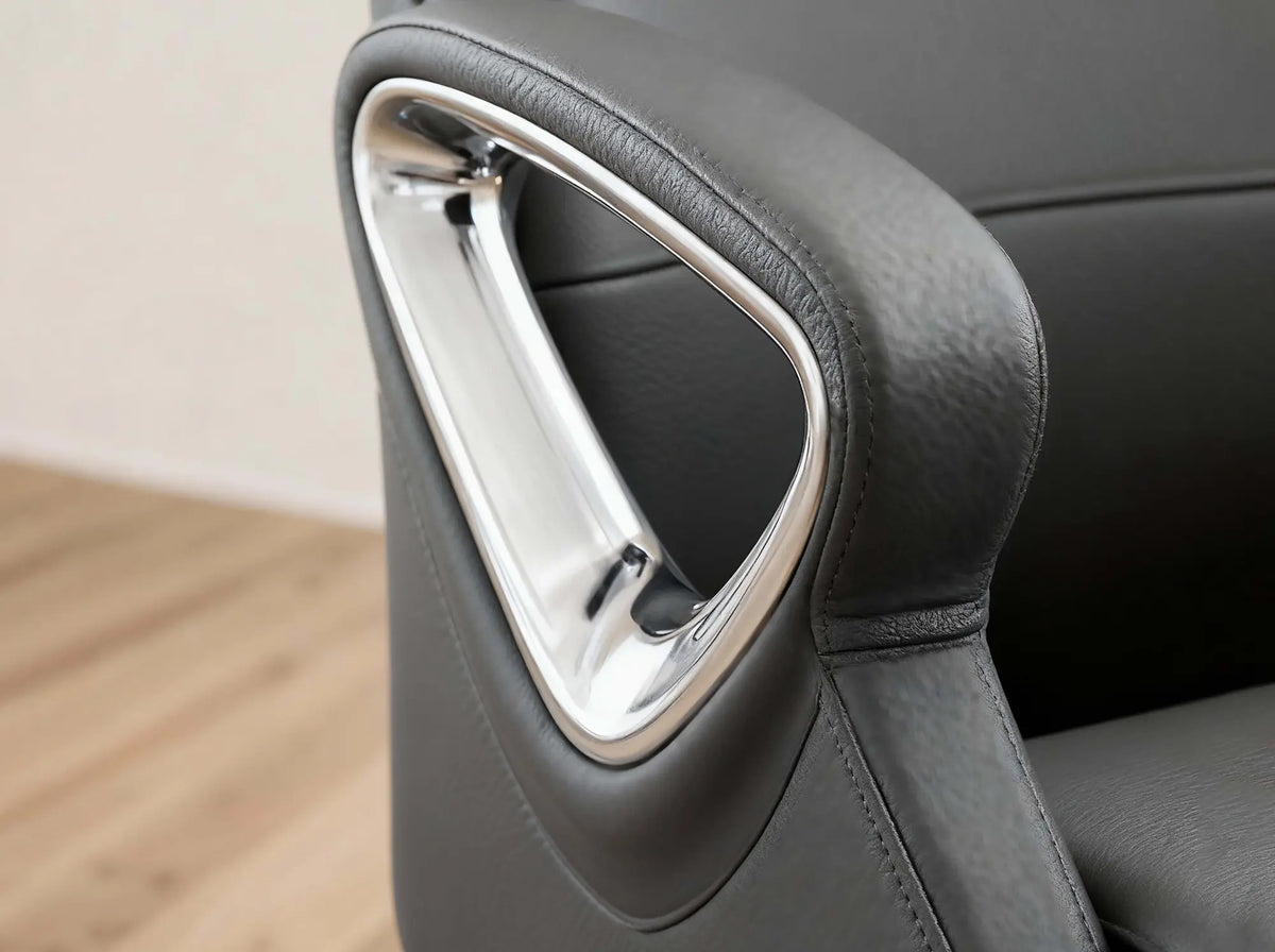 Close-up of a dark gray leather office chair armrest featuring a polished chrome triangular accent frame.