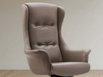 A high-back wingback office chair upholstered in taupe leather, shown from a three-quarter angle against a neutral beige wall and light wood floor.