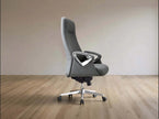 A modern gray office chair with a high back, textured fabric upholstery, and a silver five-star wheeled base, set against a minimalist beige wall and light wood floor.
