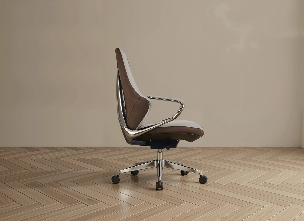 A modern office chair with a brown and white upholstered seat and back, supported by a chrome metal frame and five-star base with black casters, set against a minimalist beige wall and light wood herringbone floor.