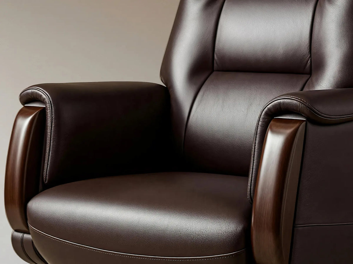 A close-up of a dark brown leather recliner chair with padded backrest and armrests, shown against a neutral beige background.