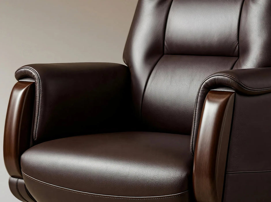A close-up of a dark brown leather recliner chair with padded backrest and armrests, shown against a neutral beige background.