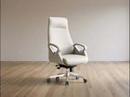 A modern high-back office chair upholstered in light beige leather, featuring chrome armrests and a five-star wheeled base, set against a minimalist beige wall and light wood floor.