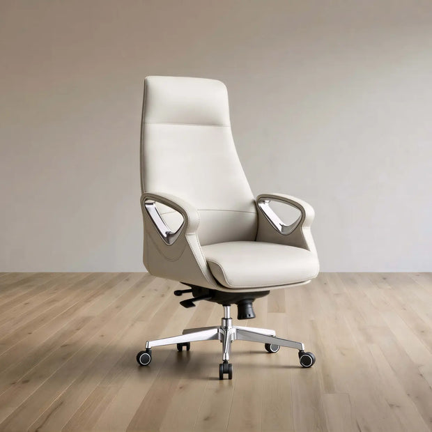 A modern high-back office chair upholstered in light beige leather, featuring chrome armrests and a five-star wheeled base, set against a minimalist beige wall and light wood floor.