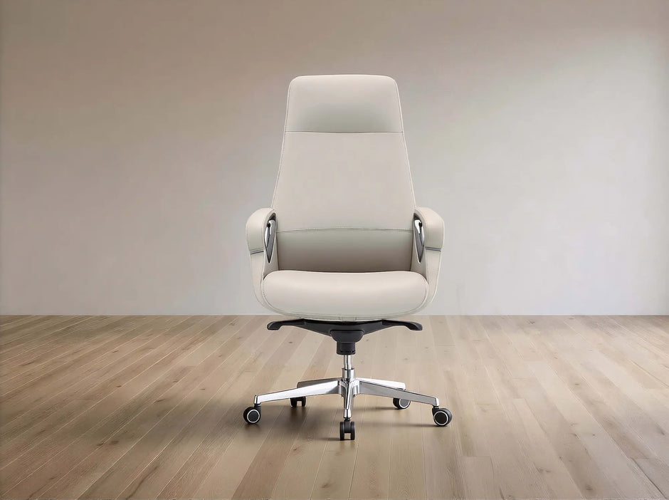 A modern high-back office chair upholstered in light beige leather, featuring chrome armrest supports and a five-star metal base with casters, set against a minimalist beige wall and light wood floor.