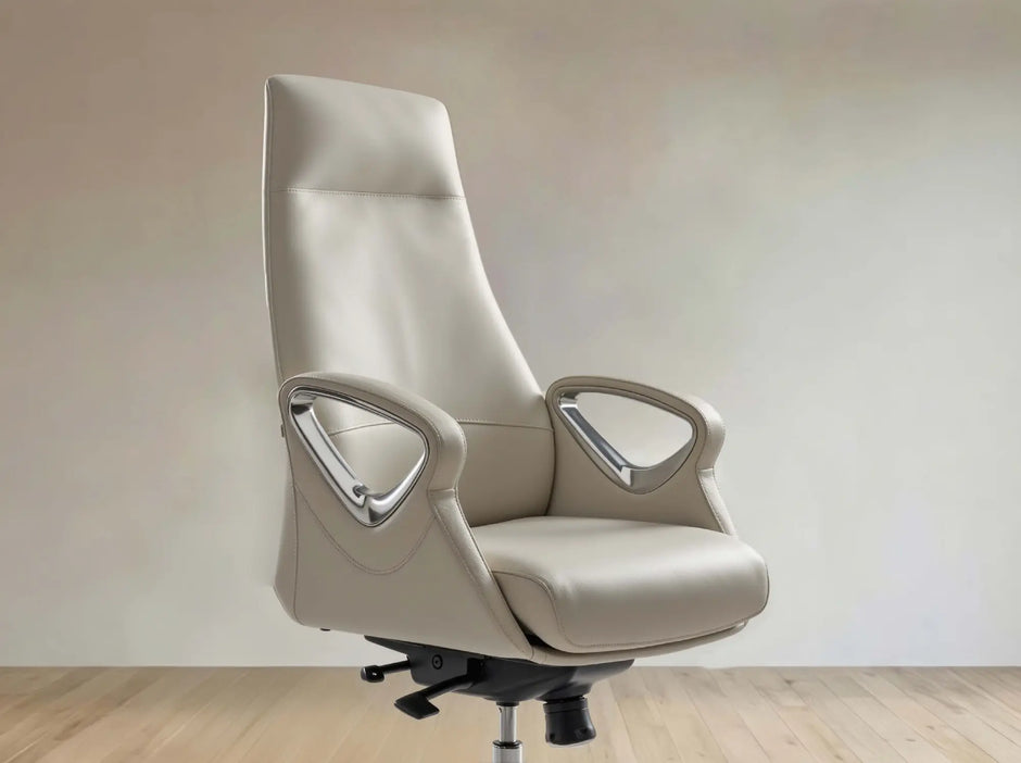 A high-back office chair upholstered in light beige leather with curved armrests and chrome accents, shown on a black wheeled base against a neutral beige wall and light wood floor.