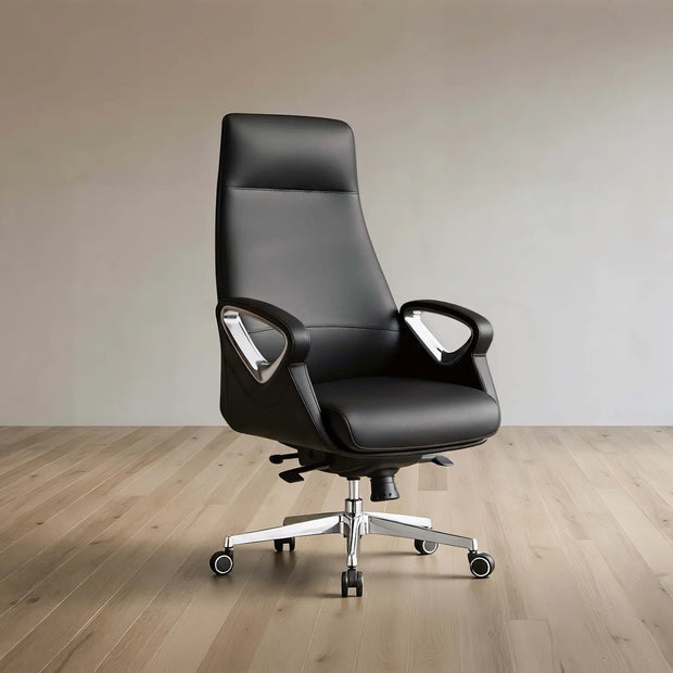 A modern black leather high-back office chair with chrome armrest supports and a five-star wheeled base, set against a minimalist beige wall and light wood floor.