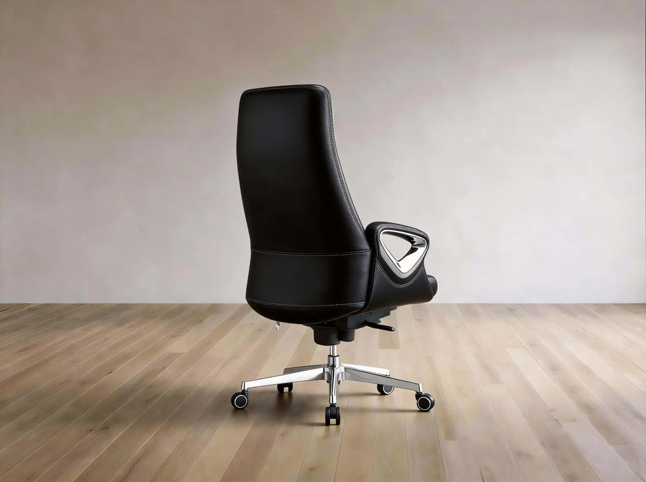 A black leather high-back office chair with a chrome five-star base and casters, shown from the side against a neutral beige wall and light wood floor.
