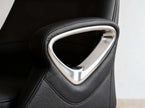 Close-up of a black leather office chair armrest featuring a prominent polished silver metallic triangular accent frame.