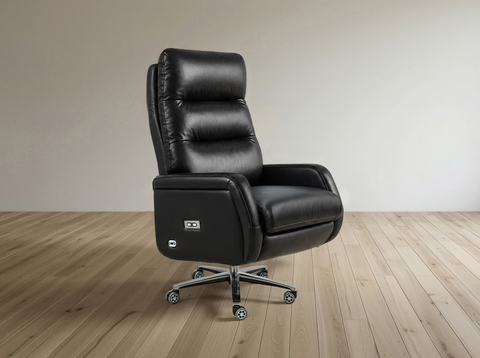 A black leather high-back recliner office chair with a power outlet on the side, mounted on a chrome five-star wheeled base, set against a minimalist beige wall and light wood floor.