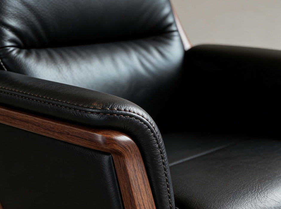 Close-up of a black leather armchair with wooden armrests.