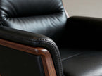 Close-up of a black leather armchair with wooden armrests.