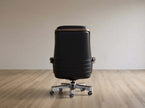Black office chair on a wooden floor with a plain wall background